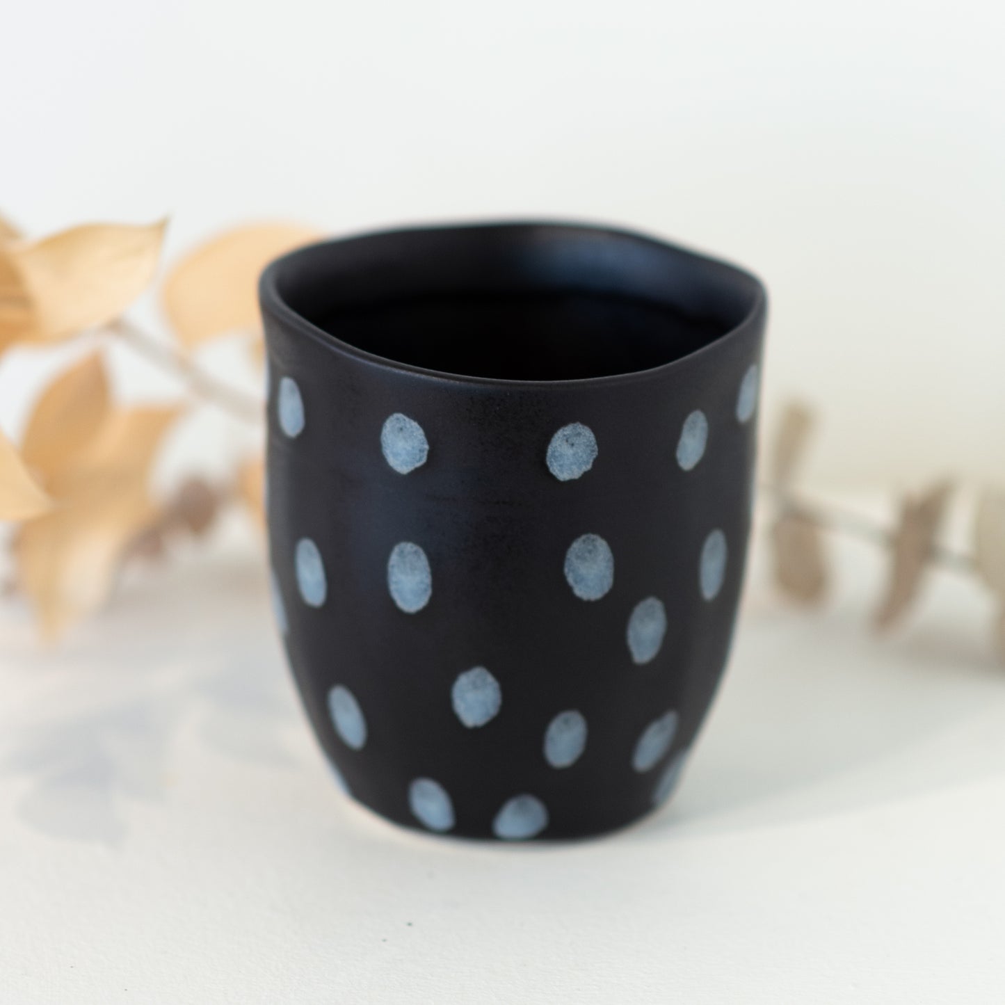 Black cup with grey/white dot patterning.