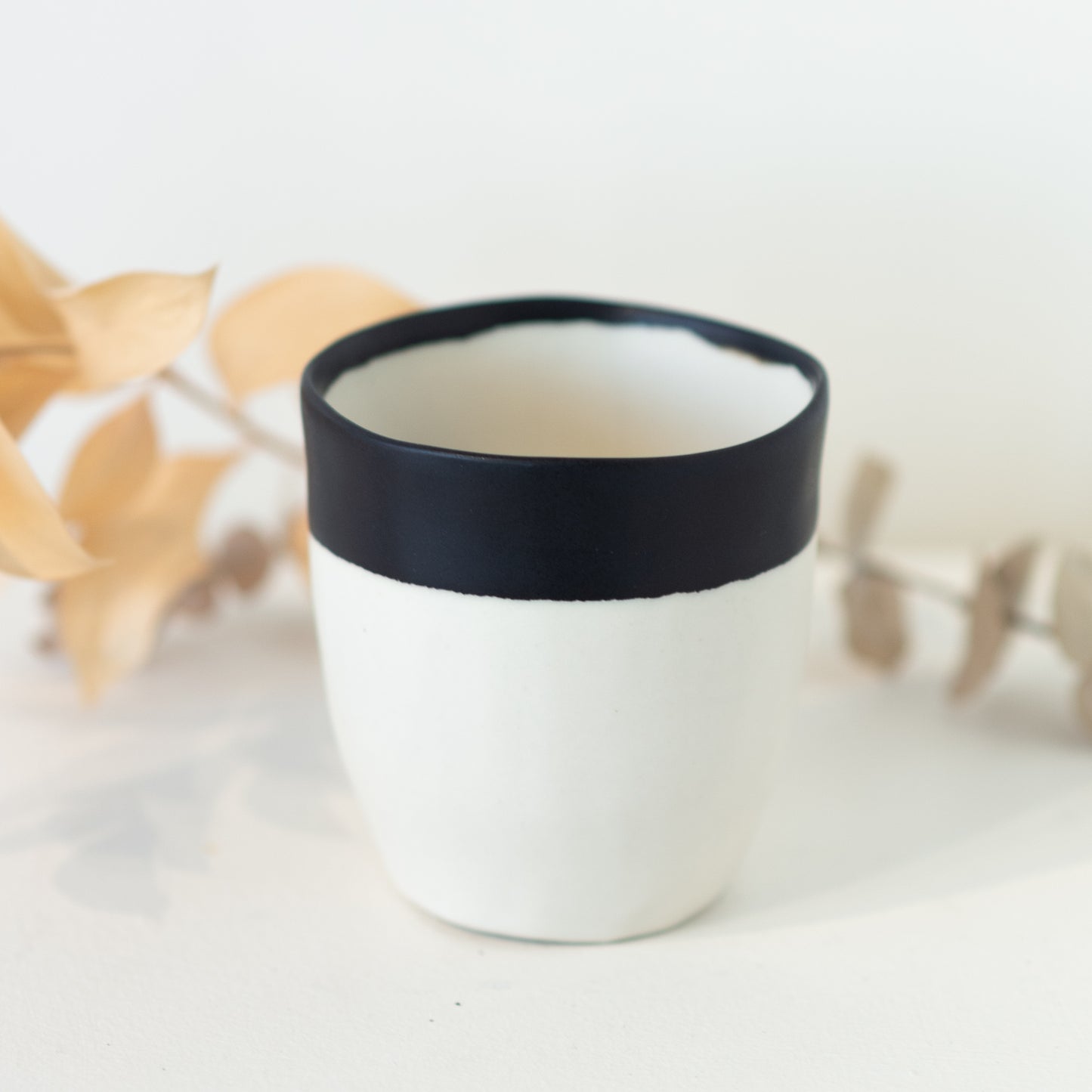White cup with black dip at top of cup.