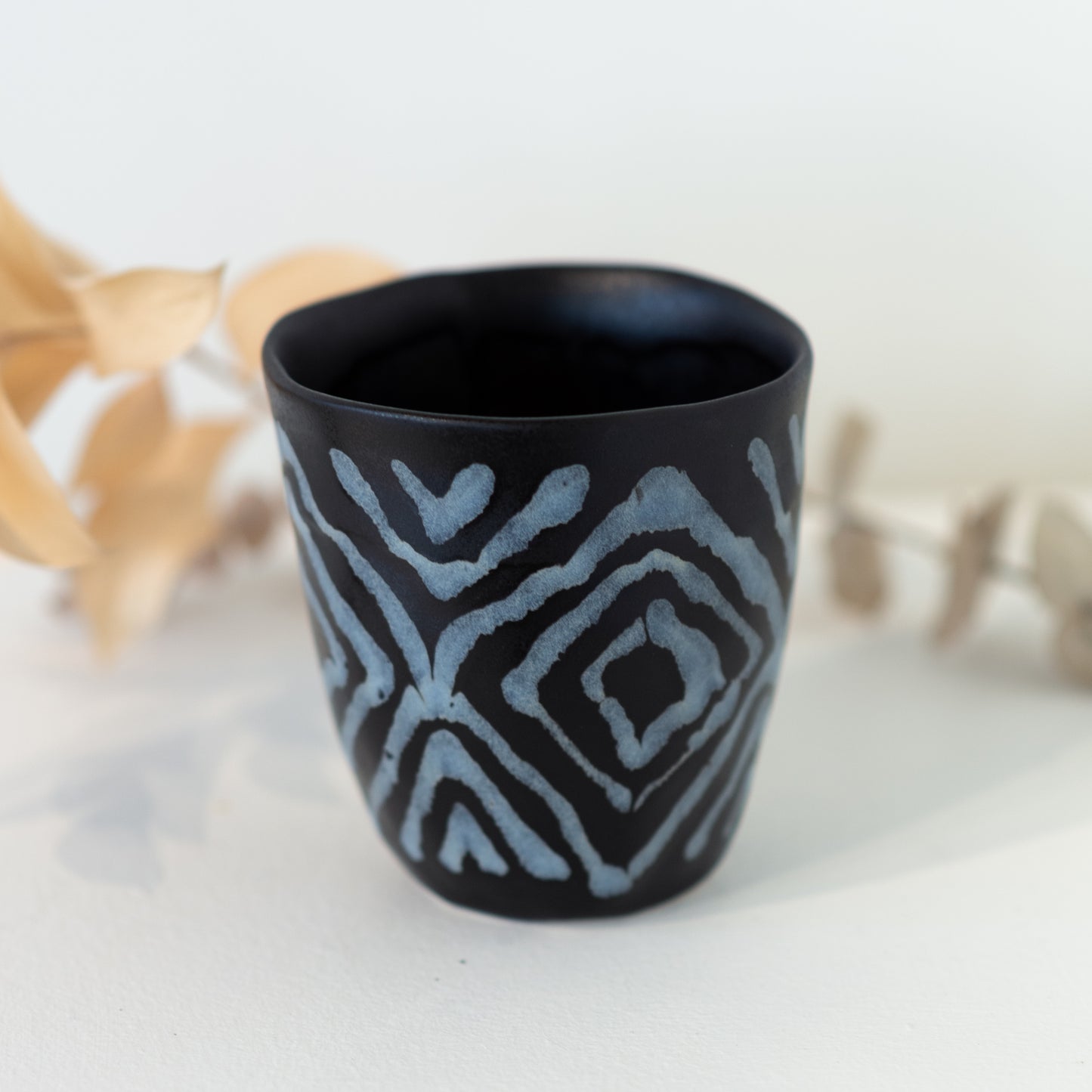 Black cup with grey/white diamond patterning.