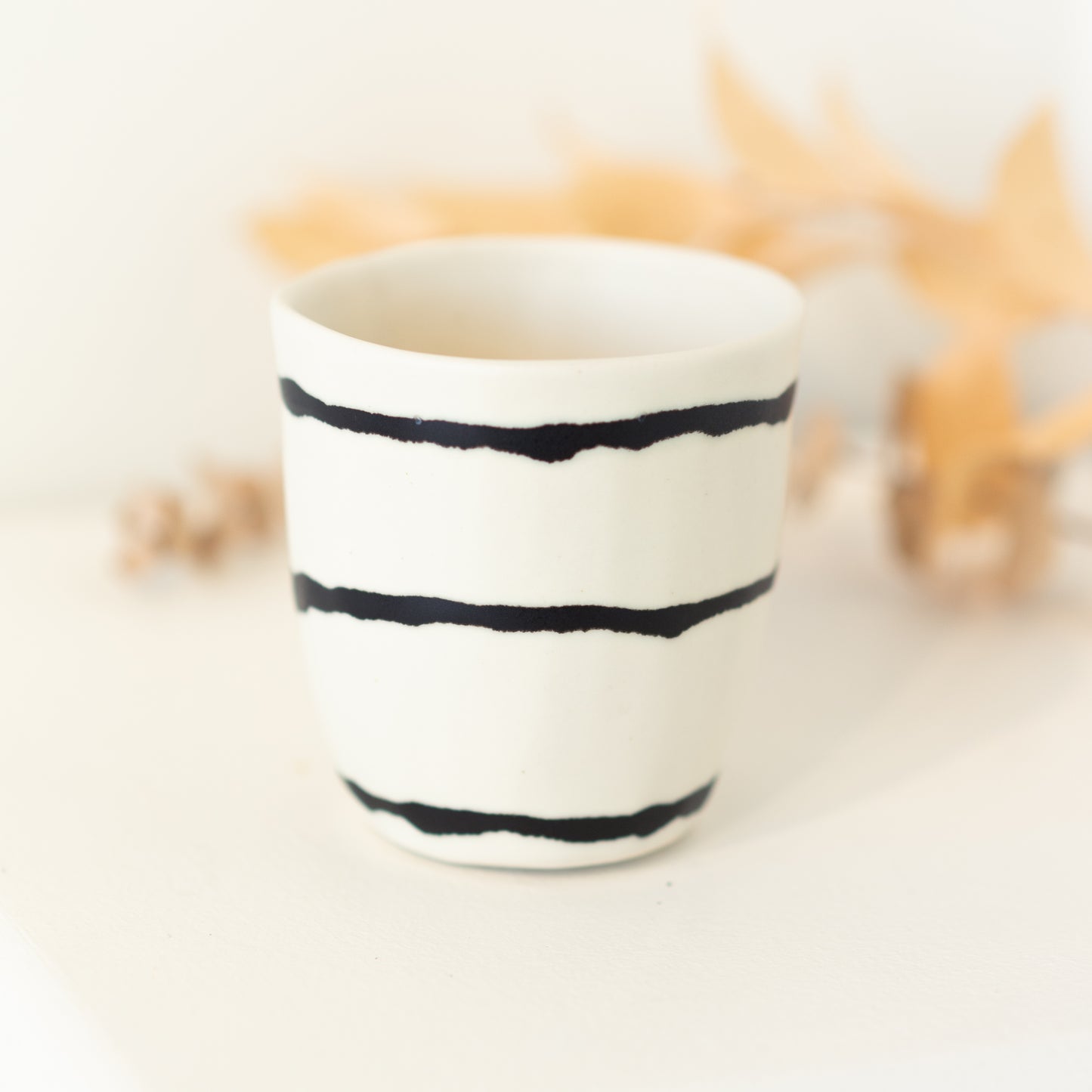White cup with black irregular horizontal lines.