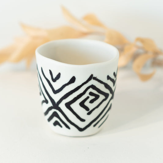White cup with black diamond patterning.