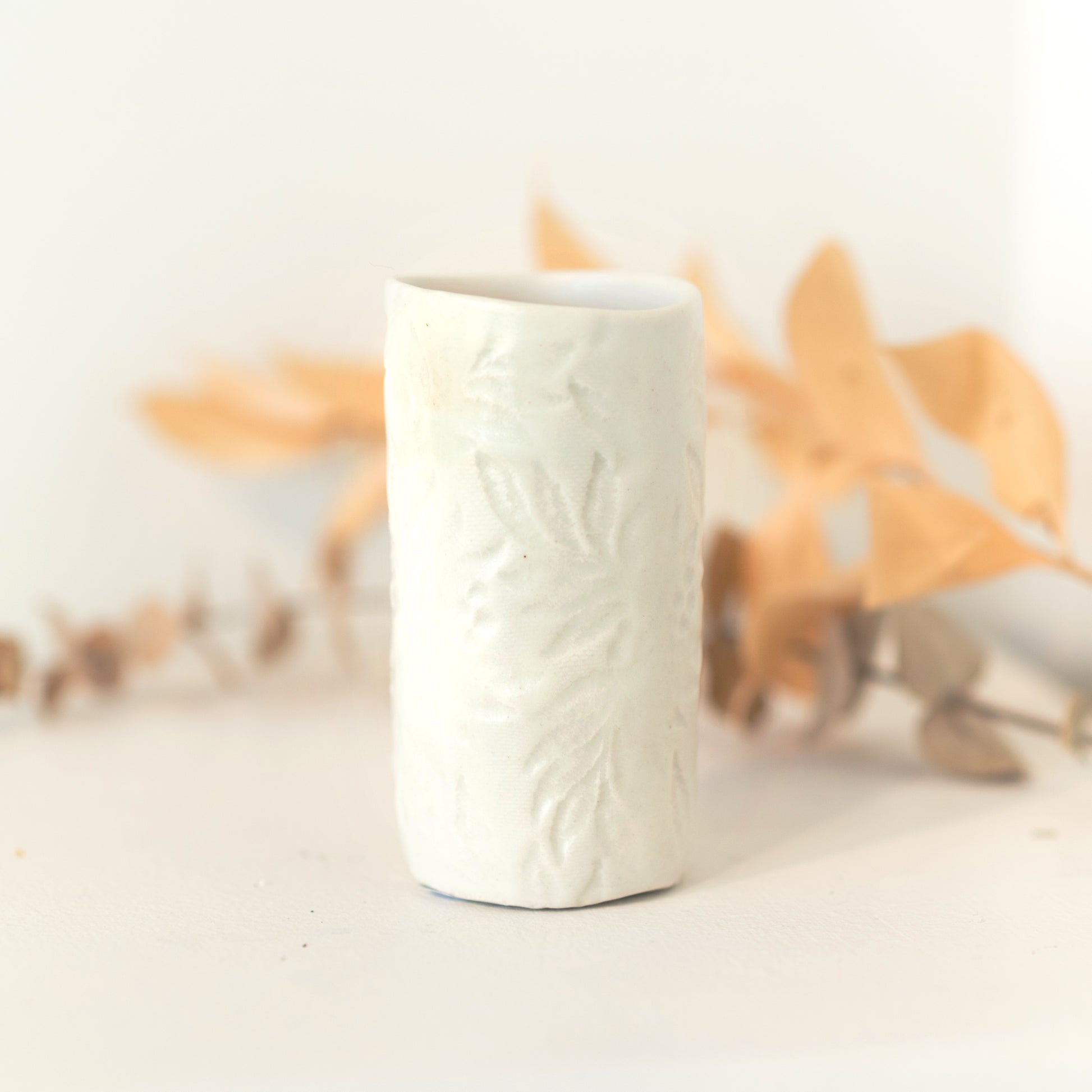 White vase with subtle imprinted floral patterning.