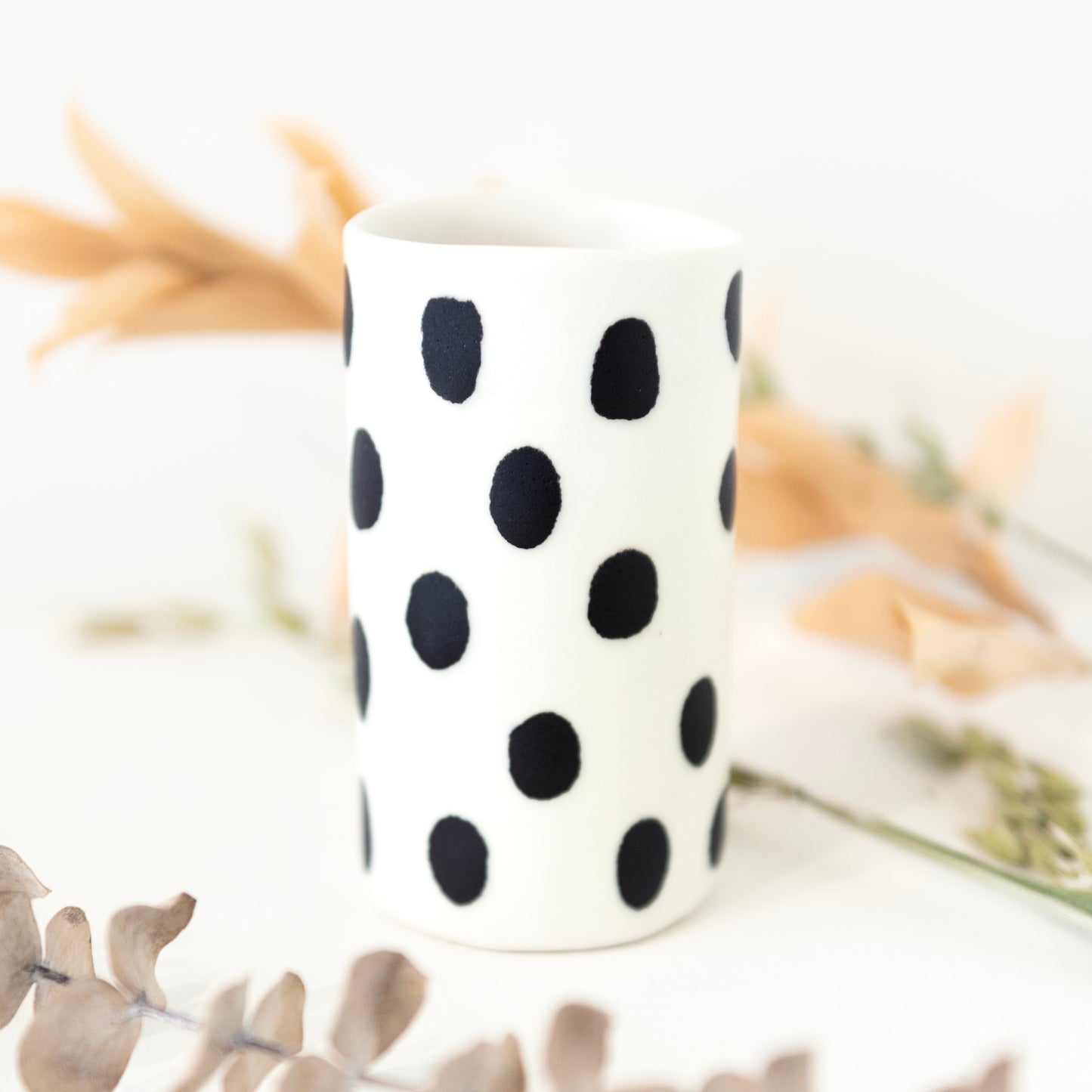 White bud vase with black dot patterning.